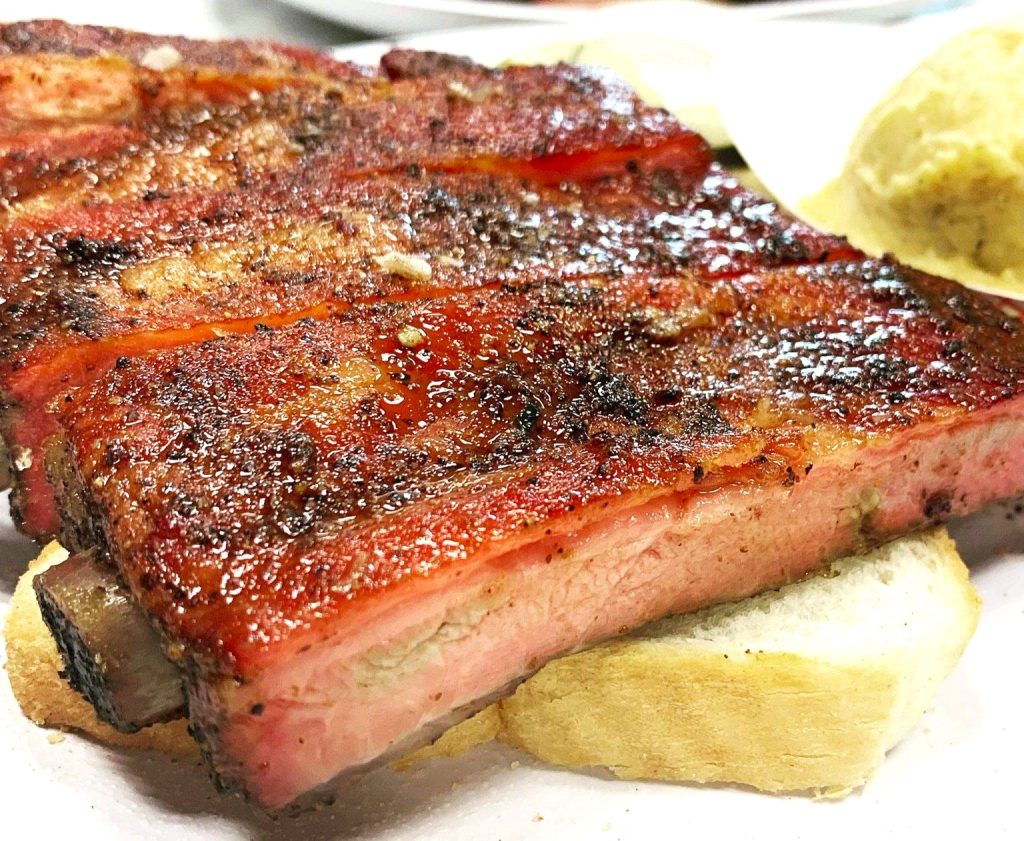 A delicious piece of meat cooked on a wood-smoked BBQ method with a sweet sauce on top by CC BBQ in New Orleans.