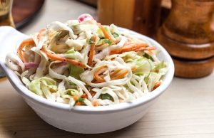 A bowl of freshly prepared coleslaw at Central City Barbeque, featuring crisp green cabbage, julienne carrots, and slivers of red onion.